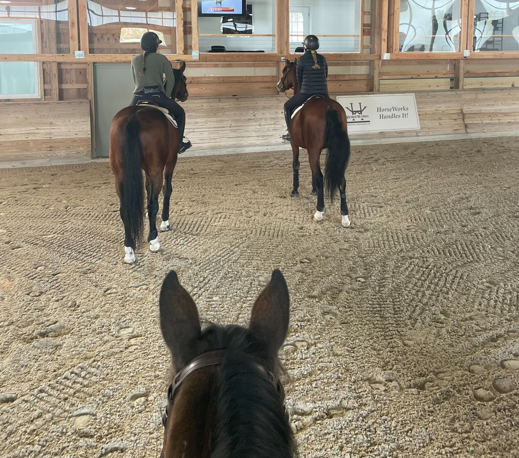 Riders in indoor arena at hunter jumper barn
